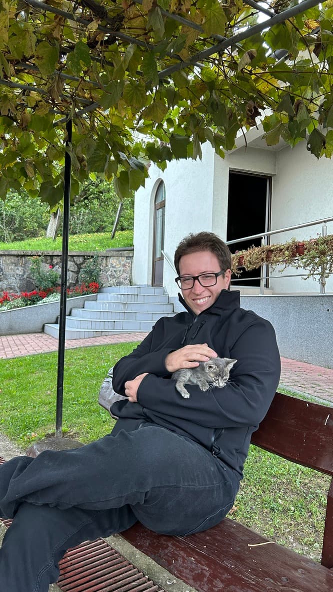 Član tima Parenja na klupi drži malo sivo mače u naručju